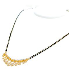 This 18k yellow gold Mangal Sutra, weighing 7.1 grams, features a tasteful dangling flower design adorned with 0.51 carats of diamonds in round and baguette shapes. The diamonds, with an F-G color and VS clarity, add exceptional brilliance and elegance. Complemented by traditional black beads, this necklace measures 19 inches in length with an additional 1-inch adjustable links. It is secured with a hook lock. Ideal for those who appreciate luxurious and sophisticated jewelry, this Mangal Sutra Traditional Yellow Gold Jewelry With Brilliant Cut, Festive Yellow Gold Diamond Jewelry, Festival Gold Jewelry With Diamond Accents, Traditional Yellow Gold Diamond Necklace With Hand-set Diamonds, Traditional Yellow Gold Diamond Necklace With Hand Set, Traditional Yellow Gold Diamond Necklace Hand Set, Traditional Hand Set Yellow Gold Diamond Necklace, Festive Gold Diamond Necklace With Accents, Traditional Yellow Gold Diamond Necklace Gift