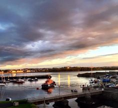 boats are docked in the harbor at sunset or sunrise time, with dark clouds overhead