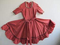 "This charming square-dance dress is still very wearable...all these years later. It is in good shape, except one faded patch on the left arm. I figure it's just part of it's vintage past. But, please look at the pictures.  I can't remember how it got faded, but perhaps a window in a closet? I've kept it safe and clean, and have not had to do much to it except wash it. Alas, I can no longer fit into it!  I made it when I joined a dance group in Middle school. It took hours to sew, and yards of fabric. Memories of listening to early rock and roll as I was sewing make it a nostalgic piece. Although the cotton is in good shape, it is old. I have not had to repair it, but you might like to add an additional closure at the very top to keep the neck secure. It's a very flattering dress, and lots Retro Cotton Vintage Dress For Daywear, 1970s Cotton Vintage Dress For Daywear, Vintage Cotton Dress With Ruffles, Cotton Vintage Dress With Ruffles, Red Cotton Vintage Dress, 1950s Cotton Vintage Dress For Vintage Fashion Events, 1950s Cotton Vintage Dress, 1950s Style Cotton Vintage Dress, Square Dance Dresses