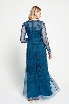 a woman wearing a blue dress with sheer sleeves and beaded details on the shoulders