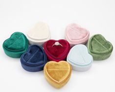 six heart shaped rings in various colors on a white surface with a diamond ring inside the middle