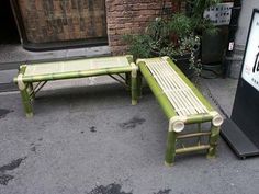 two green benches sitting next to each other in front of a sign and potted plants