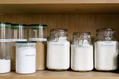 there are many jars with different types of food in them on the shelf next to each other