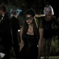 a woman in a black dress wearing a mask