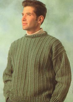 a man in a green sweater is posing for the camera with his hands in his pockets