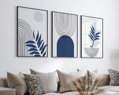 three blue and white paintings hang on the wall above a couch in a living room