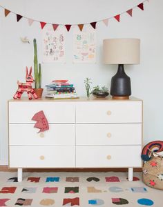 a white dresser sitting next to a lamp on top of a rug