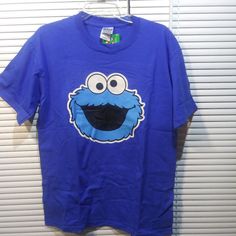 a blue shirt with an image of a cookie monster on the front and bottom, hanging from a hanger