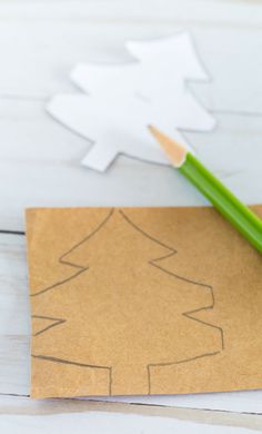 a pencil sitting on top of a piece of paper next to a cut out christmas tree