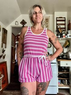 Ugh this is so cute but so short for my torso Amazing 80's striped romper  Magenta purple and white striped romper  Tank sleeves with cute buttons on top of sleeves  Elastic waistline  Ties around the waist it's connected in back  One pocket on one side  Cotton polyester material  Great vintage condition  Short shorts  Tag reads size medium  Measurements are approximate and taken flat so please double bust waist and hips for more accurate sizing  Bust: 15.5 in  Waist: 15.5 in stretched to 17 in Summer Striped Tops For Loungewear, Striped Tops For Summer Loungewear, Vertical Stripes Tops For Summer Loungewear, Retro Pink Summer Jumpsuits And Rompers, Retro Pink Jumpsuits And Rompers For Summer, Pink Retro Summer Jumpsuits And Rompers, Summer Striped Cotton Jumpsuits And Rompers, Striped Cotton Jumpsuits And Rompers For Summer, Casual Striped Fitted Jumpsuits And Rompers