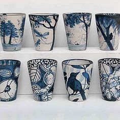 nine blue and white cups are lined up on a shelf