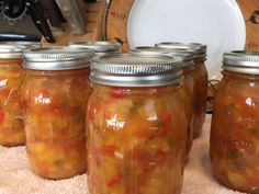 four jars filled with pickles sitting on top of a table