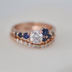 a diamond and blue sapphire ring set on top of a white surface with two diamonds in the middle