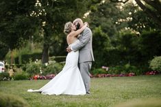 a bride and groom kissing in the grass