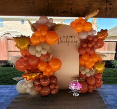 an arch made out of balloons with the words happy thanksgiving written in gold and orange