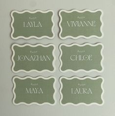 four place cards with names on them in white and green colors are displayed against a gray background