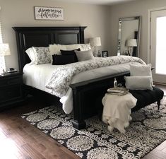 a bedroom with a large bed, black dressers and white blankets on the floor