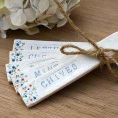 three wooden tags tied with twine on top of a table next to some flowers