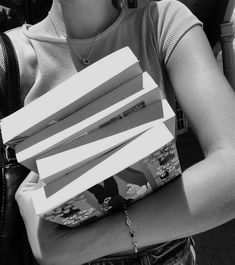 black and white photograph of woman holding stack of books