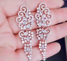 A beautiful pair of bridal earrings that is sure to make a bold statement on your Wedding Day! Adorned with glowing cubic zirconia that capture the light from every angle with a perfectly translucent appeal, the earrings are rhodium/rose gold plated for a bright finish which enhances the intricate detailing and conveys a modern take on old elegance. Length of the earring is 2.4" (approx. 6.1cm); Width: 0.7" (approx. 1.8cm); Weight: 12g. Available in Silver and Rose Gold finishes. To make your ch Wedding Earrings Silver, Cubic Zirconia Bridal Earrings, Silver Earrings Wedding, Wedding Earrings, Earrings Silver, Bridal Earrings, On Your Wedding Day, Exquisite Design, Rose Gold Plates