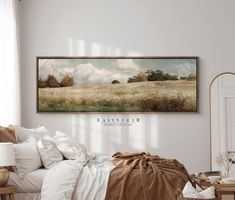 a bedroom with white walls and a large painting on the wall