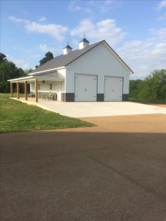 a large white barn sitting on top of a lush green field