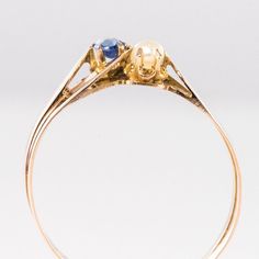 This is part of Chairish’s Fine Jewelry assortment.  Ring in 18 karat rose gold.  Lovely antique charm ring, it is made of a flat double ring like a gold ribbon which asymmetrically retains a natural pearl and a cushion-cut sapphire on its top.  Sapphire weight : approximately 0.14 carat.  Diameter of the pearl : approximately 2.5 / 3 mm.  Height : 7.32 mm, Width : 13.28 mm, Thickness : 3.87 mm approximately, Width at the base of the ring : 3.7 mm.  Total weight of the jewel : approximately 2.2 Sapphire Antique Ring, Black Pearl Ring, Pearl Rings Vintage, Graduation Rings, Edwardian Ring, Gold Sapphire Ring, Pearl Engagement Ring, Charm Ring, Vintage Cocktail Ring