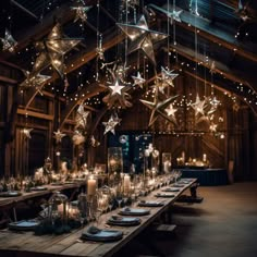 a wooden table topped with lots of candles and stars hanging from the ceiling above it