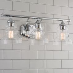 three light bathroom fixture with clear glass shades on the wall and white tile backsplash