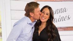 a man and woman kissing each other in front of a sign