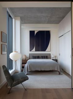 a bedroom with a bed, chair and artwork on the wall