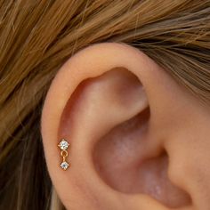 a woman's ear is shown with three small diamond studs on the side