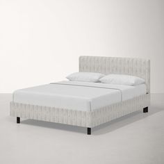 a bed with white sheets and pillows on it