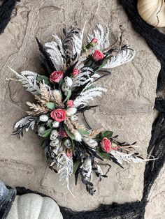 an arrangement of flowers and feathers on a rock