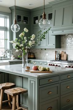 a kitchen with green cabinets and white flowers in a vase on the island countertop