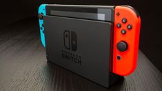 an orange and blue nintendo switch sitting on top of a wooden table