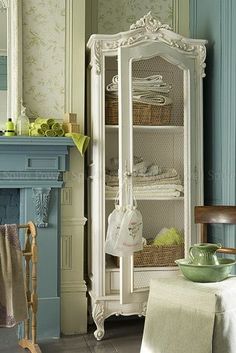 a white china cabinet sitting next to a fireplace