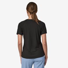 a woman in black shirt and blue pants looking down at the back of her t - shirt