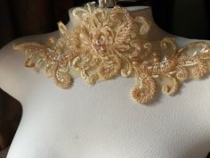 a white mannequin with gold lace and flowers on it's neckline