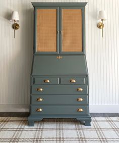 an old dresser is painted green and gold with brass knobs on the doors, along with two wall sconces