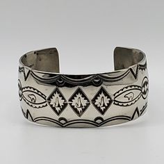 an open cuff bracelet with black and white designs on the outside, in sterling steel