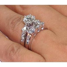 a woman's hand holding a ring with three stones on it and two wedding bands