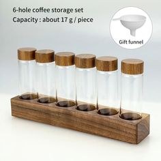 six glass bottles with wooden lids are lined up in a row on a stand, each containing an individual's own funnel