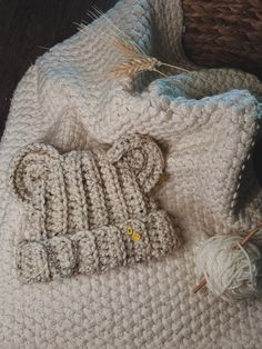 a crocheted teddy bear laying on top of a blanket next to a ball of yarn