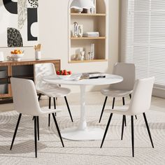 a white table with four chairs around it in a living room next to a book shelf