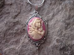 "Beautiful Virgin Mary cradling baby Jesus cameo necklaces I can make matching earrings, brooch and a bracelet also, so please feel free to message me, and I will set up a custom/reserved listing. The cameos are gorgeous, choose from black or pink I do have other colors and styles, so please do browse, I can make any cameo in my shop into this pretty necklace, so browse and message me with a custom order The pretty setting is about 1 1/2\" long, please do see the photo The chain is a 22\" .925 s Personalized Pink Jewelry For Christmas, Pink Adjustable Christmas Jewelry, Personalized Jewelry For Mother's Day Collectible, Red Cameo Necklace For Gift, Handmade Pink Jewelry For Christmas, Spiritual Jewelry For Christmas Gift, Red Cameo Jewelry Gift, Cameo Jewelry Gift, Cameo Round Jewelry Gift