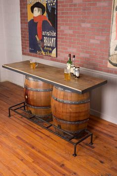 two wine barrels sitting on top of a wooden table in front of a brick wall