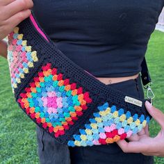 a woman is holding a crocheted purse in her hands and wearing a black shirt