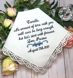 a white handkerchief with embroidered words on it next to flowers and a silver canister