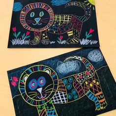 two black paper paintings with colorful designs on them, one has a cat and the other is a tiger